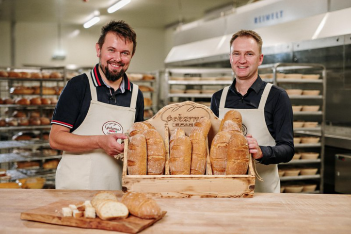 Zwei Männer halten ein Korb voller Brot