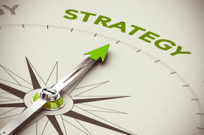 Conceptual 3D render image with depth of field blur effect. Compass needle pointing the green word strategy over natural paper background.